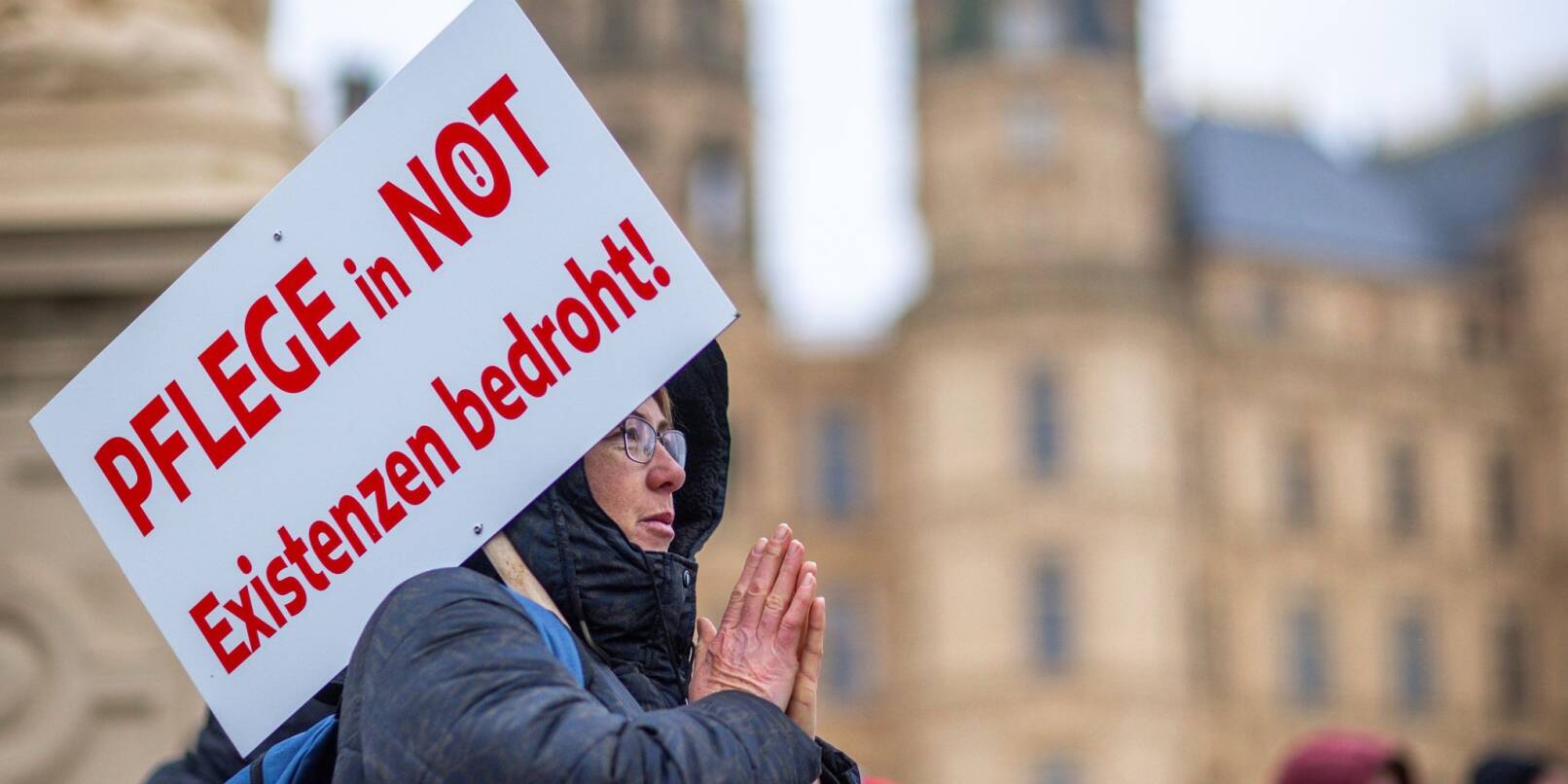 Bei einer Protestaktion vor dem Schweriner Landtag hält eine Teilnehmerin ein Schild mit der Aufschrift «Pflege in Not - Existenzen bedroht!».