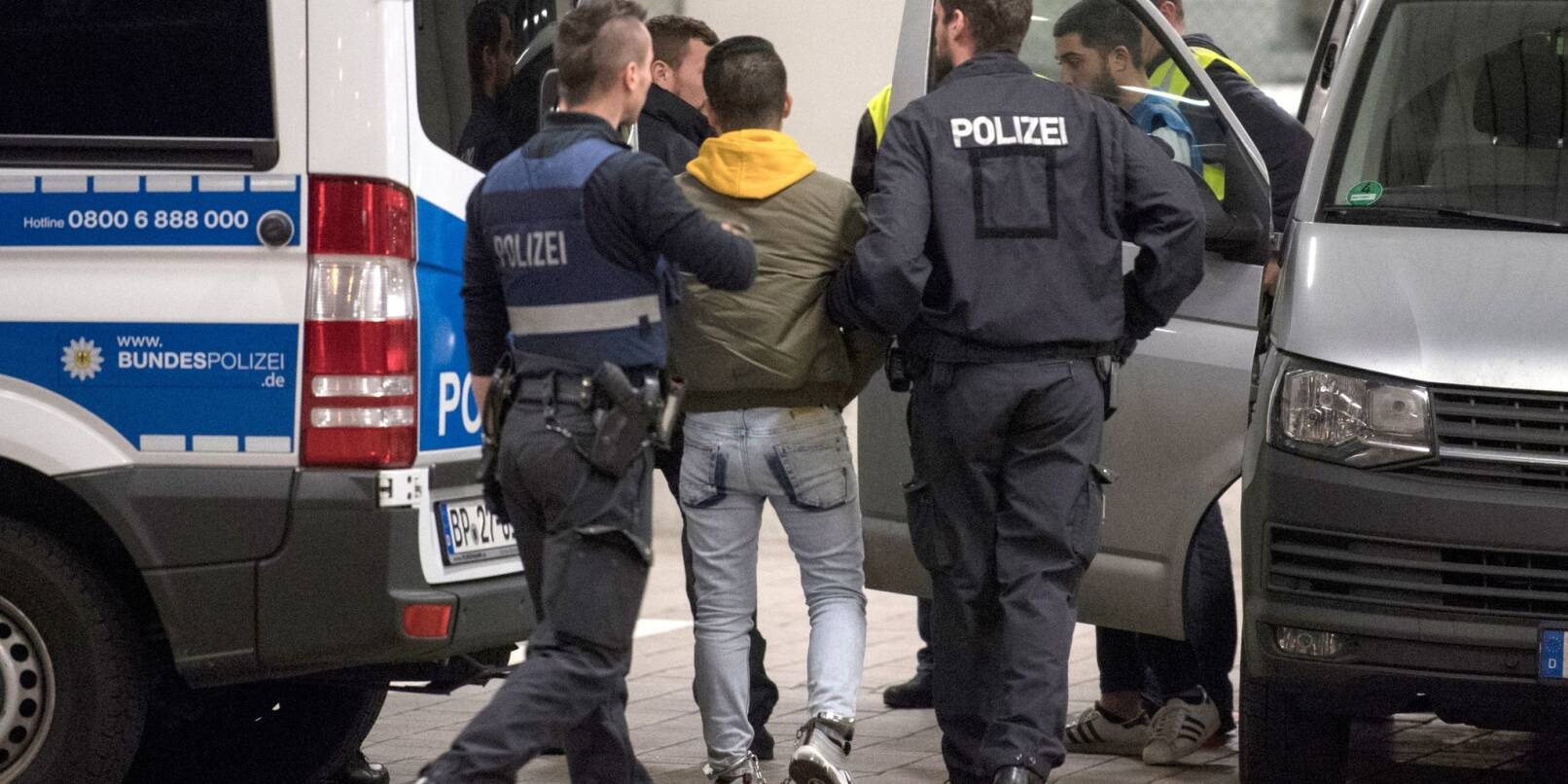 Hand und Fußfesseln trägt ein junger Mann aus Afghanistan, den Polizisten zur Abschiebung zum Flughafen bringen.