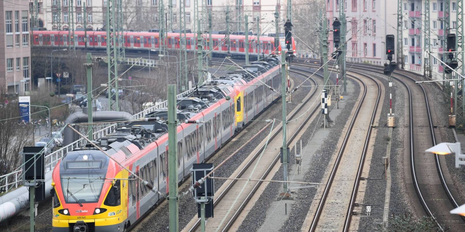 Ein Zug der Hessischen Landesbahn (l) und eine S-Bahn fahren in den Bahnhof Frankfurt am Main Messe ein.