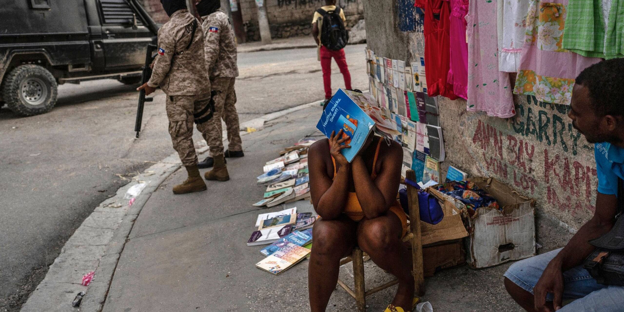 Polizisten patrouillieren neben einer Straßenhändlerin in der Innenstadt von Port-au-Prince. Bewaffnete Gruppen kontrollieren große Teile von Haitis Hauptstadt. Zuletzt eskalierte die Gewalt weiter. Mehr als 1500 Menschen wurden in den ersten drei Monaten des Jahres getötet.