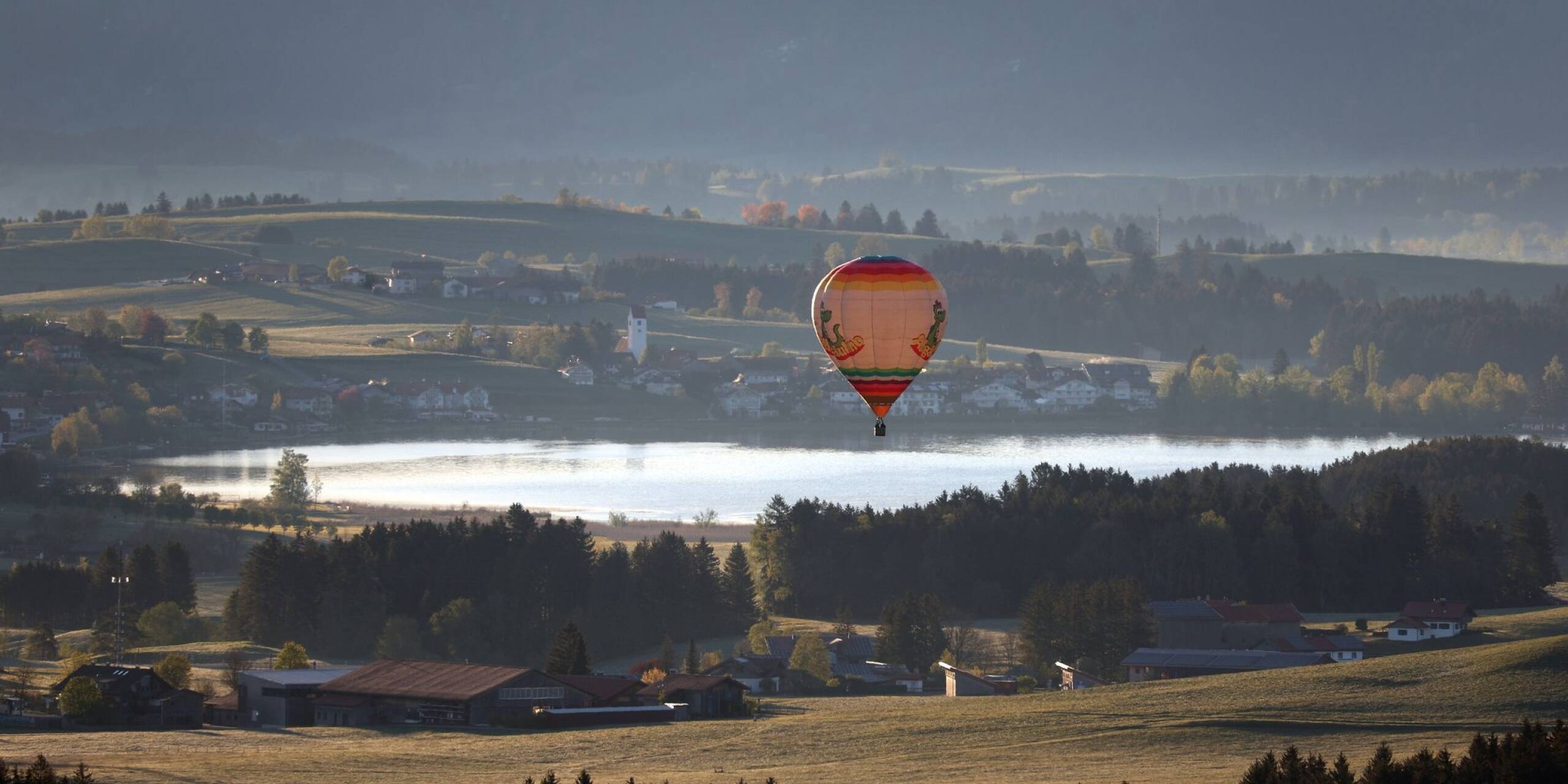 Ein Heißluftballon gleitet über den Hopfensee im Allgäu.