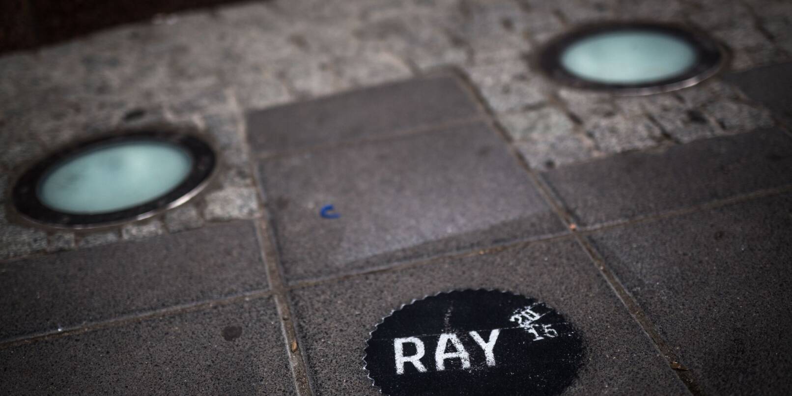Ein auf den Gehweg gesprühtes Zeichen weist auf die «Triennale der Fotografie RAY» hin.