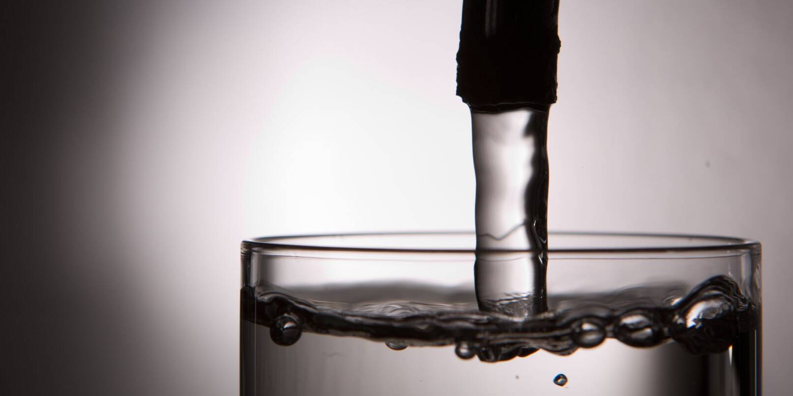 Leitungswasser läuft aus einem Wasserhahn in ein Glas.