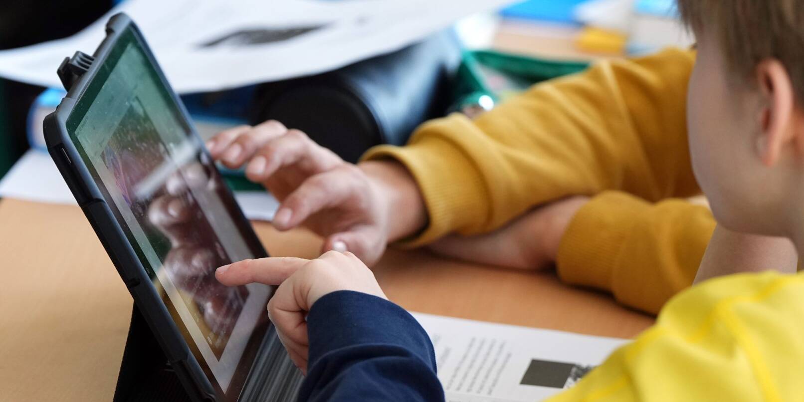 Schüler lösen im Unterricht an einem Tablet eine Aufgabe.