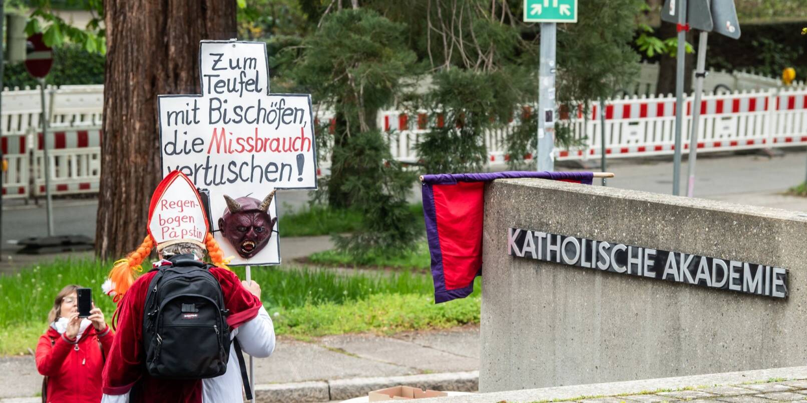 Ein Mann hält vor der Katholischen Akademie ein Schild mit der Aufschrift «Zum Teufel mit Bischöfen, die Missbrauch vertuschen!».