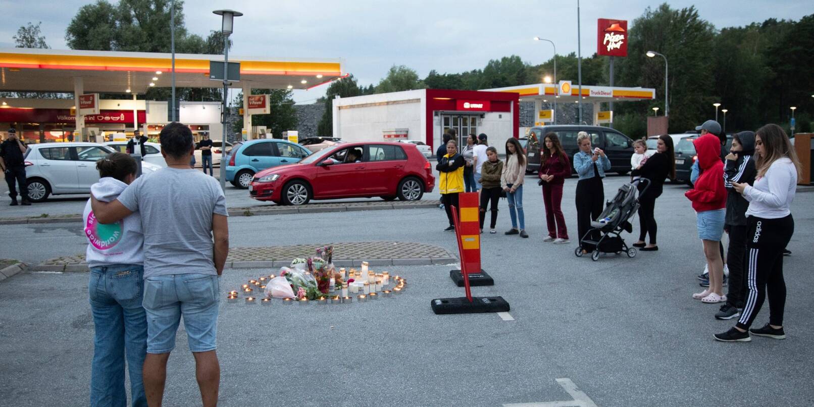 Menschen stehen neben Blumen und Kerzen auf einen Parkplatz, wo die zwölfjährige Adriana aus einem vorbeifahrenden Auto heraus erschossen wurde (Archivbild).