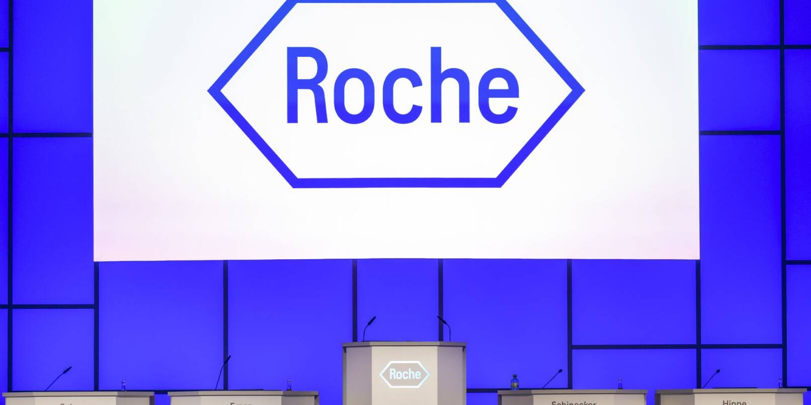 Das Logo des Pharmaunternehmens Roche ist vor einer Hauptversammlung auf der Bühne zu sehen.