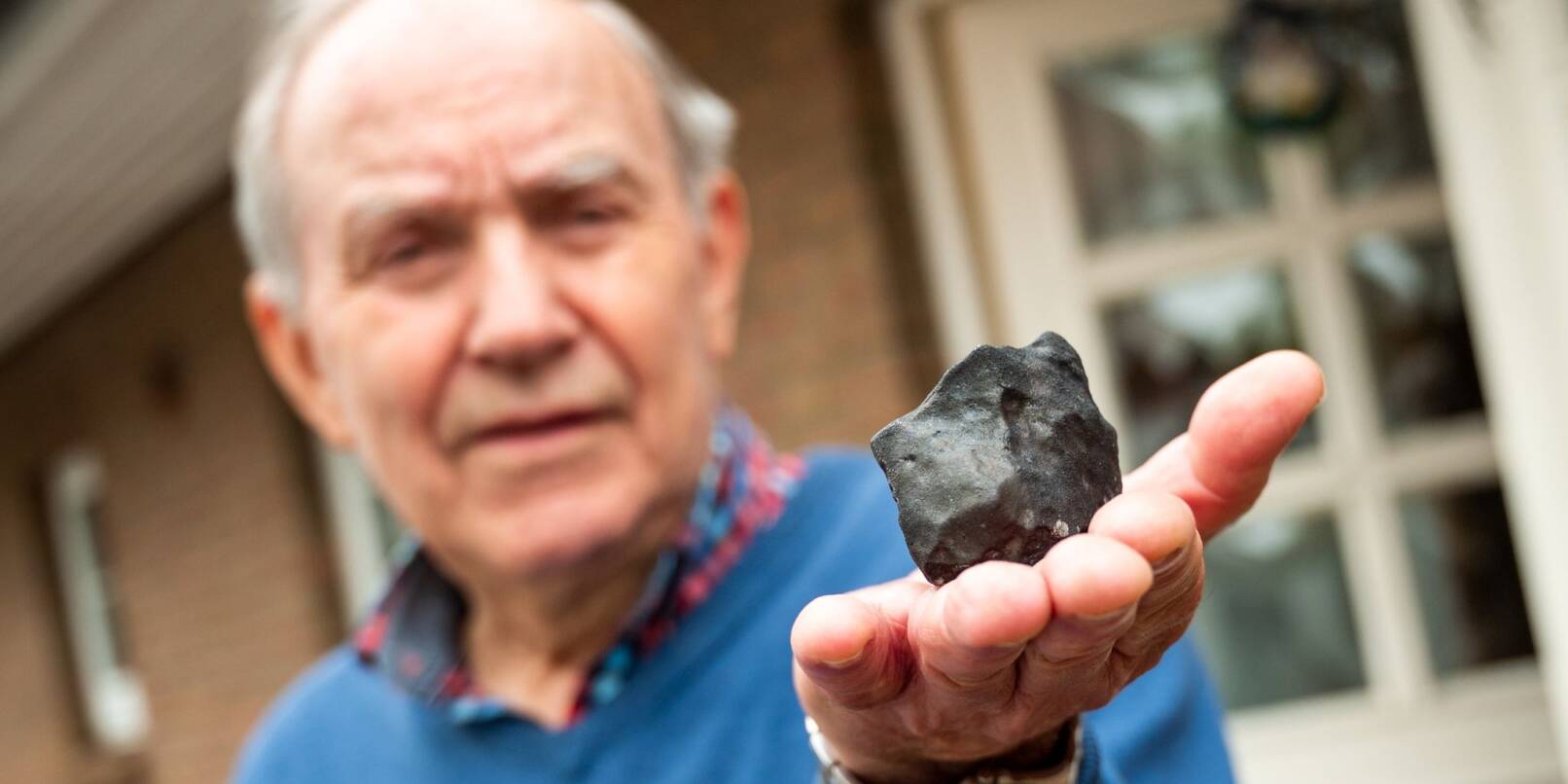 Wilfried Labusch hält einen kleinen Meteoriten, der in sein Haus niedergegangen ist.