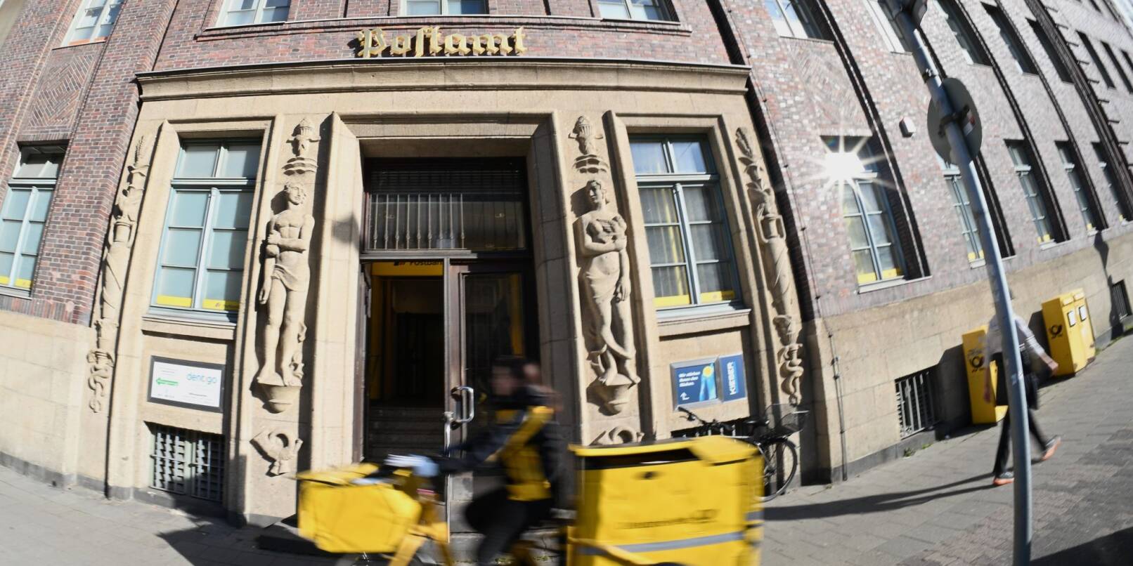 Eine Briefträgerin fährt an einer Postfiliale vorbei - vielleicht ist auch sie eine Beamtin? Eine Briefträgerin fährt an einer Postfiliale vorbei - vielleicht ist auch sie eine Beamtin?