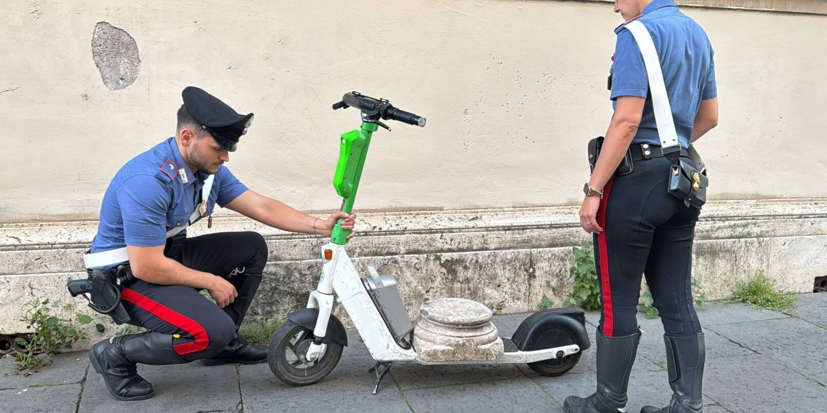 Zwei Carabinieri begutachten den Marmorsockel auf einem elektrischen Leihroller. Zwei Carabinieri begutachten den Marmorsockel auf einem elektrischen Leihroller.