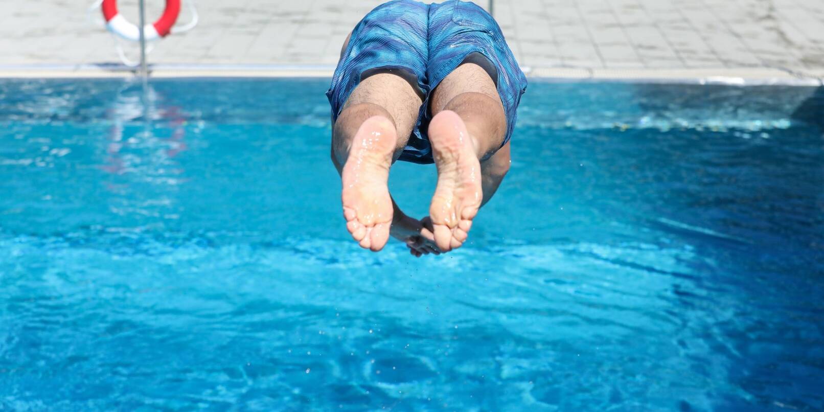 Ein Mann springt von einem Sprungbrett kopfüber ins Wasser.