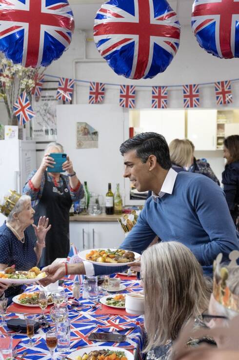 Premierminister Rishi Sunak (m.) serviert das Essen für den Lunch Club einer Gemeindegruppe in Hertfordshire.