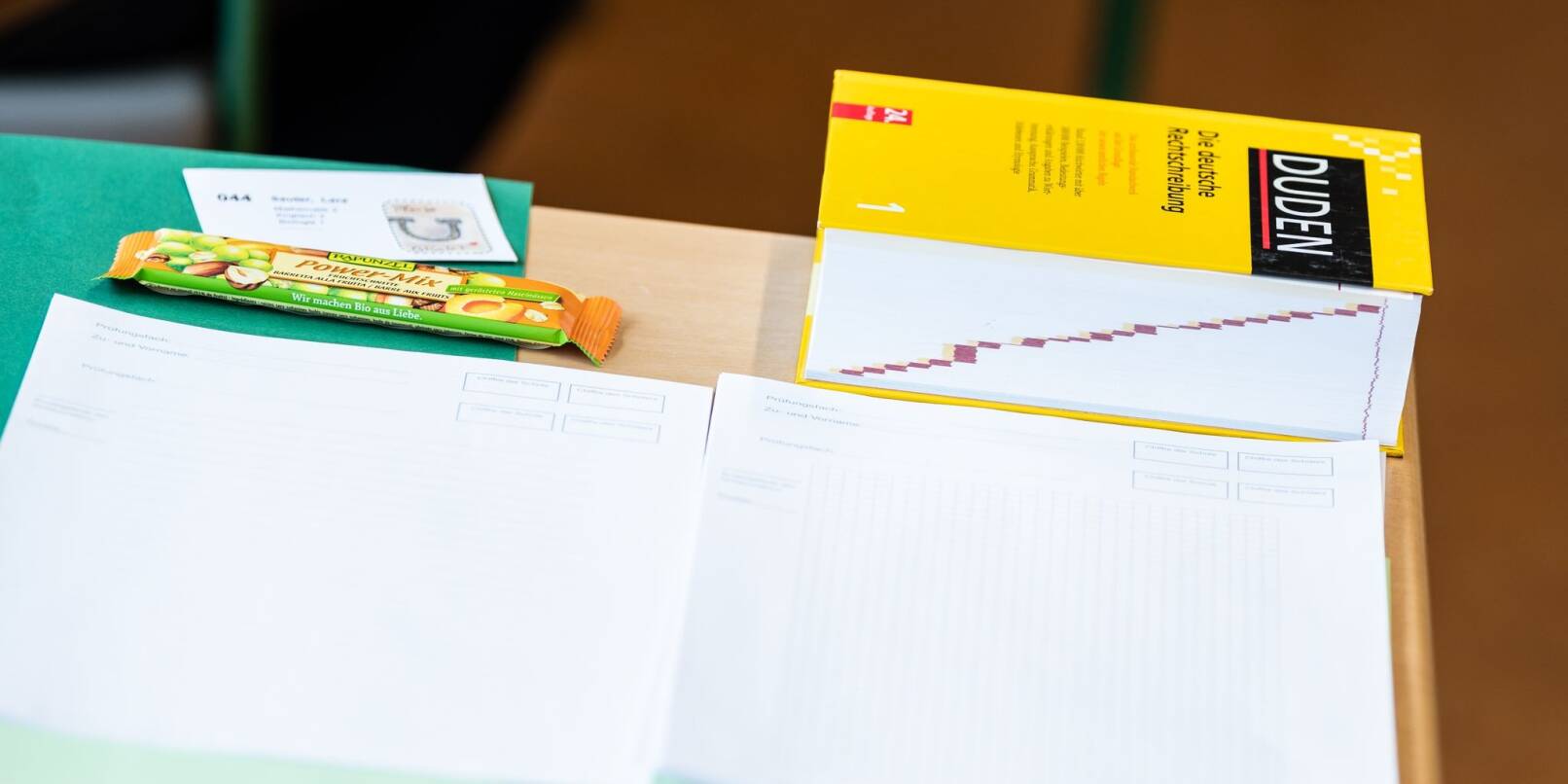 Ein Duden, sowie die Prüfung liegen vor Beginn der schriftlichen Abiturprüfung in Biologie auf einem Tisch in einem Klassenzimmer im Leibniz-Gymnasium.